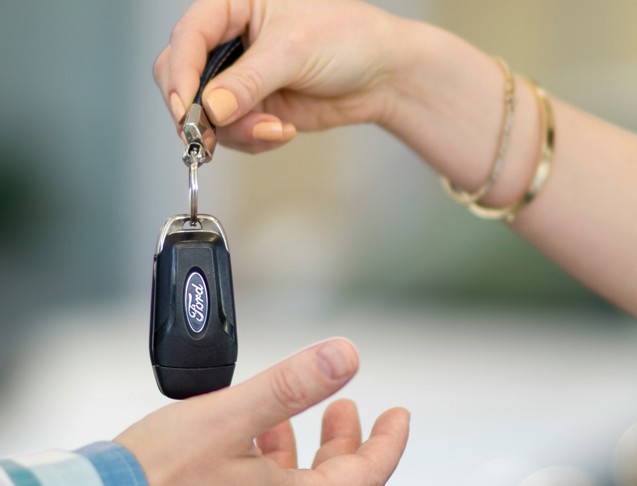 a person handing a car key to another person