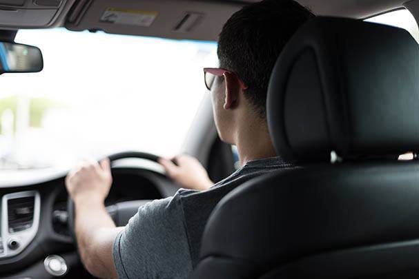 A young man behind the wheel of a car.