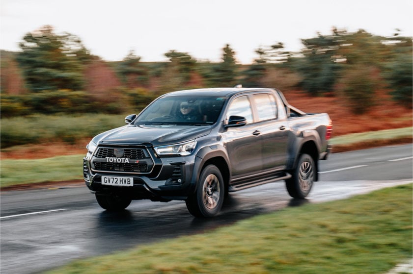 Toyota Hilux in black driving on a country road