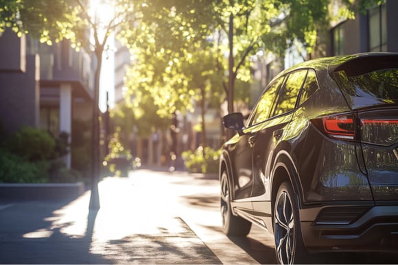 Rear view of a modern SUV parked on a sunlit city street lined with trees and contemporary buildings