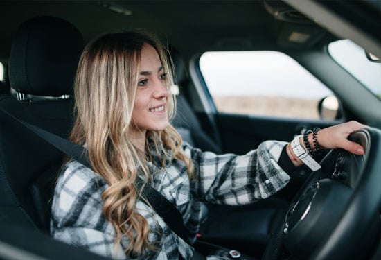 A teenage girl in the driver seat of a new car