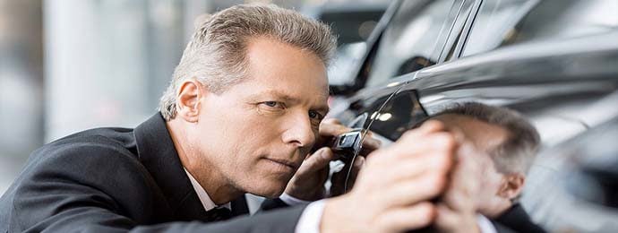 man inspecting vehicle for damage