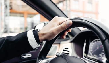Person dressed smart holding steering wheel