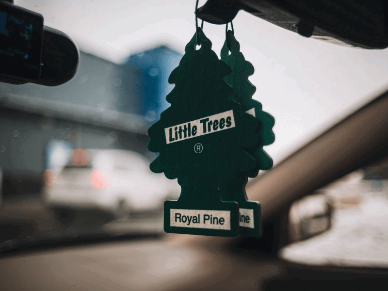 Green tree-shaped air freshener hanging from car mirror, depicting 'Royal Pine' scent.