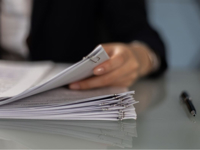 Close-up of a professional organizing a stack of documents on a desk.