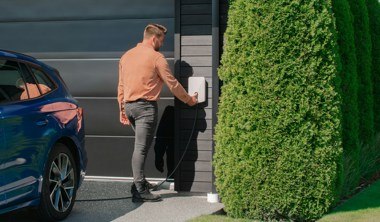 man using electric car charging point at home