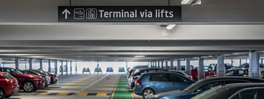 cars parked on a multi level parking garage with directional signage