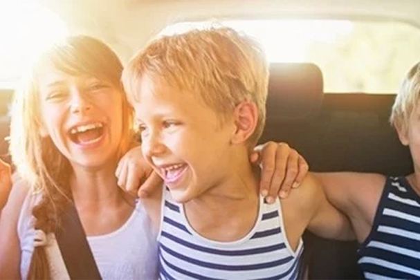 Three laughing children sat in the back of the car.