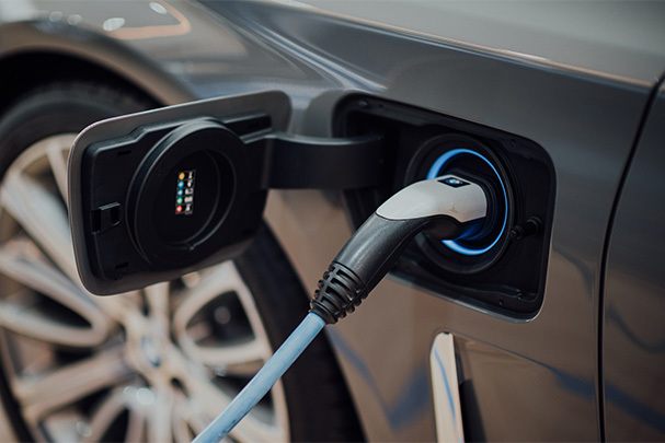 A close up of an electric car with its charging cable attached.