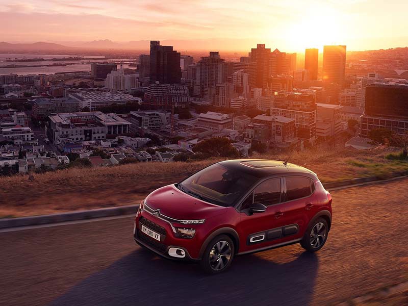 Red Citroen C3 Hatchback overlooking city at sunset