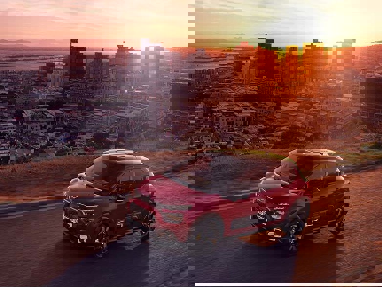 Red Citroen C3 Hatchback overlooking city at sunset