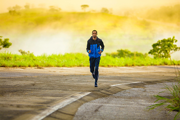 A photo of a person running on a street with a car passing by for an article on staying safe while running on the road.