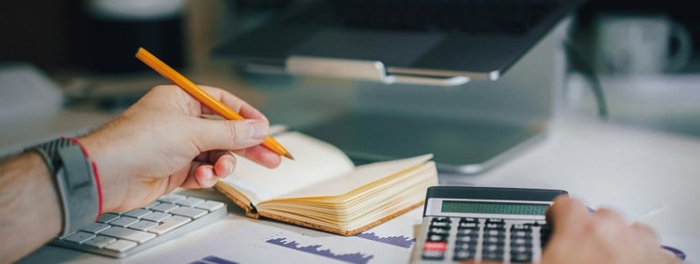 a person sitting at a desk with a calculator and a notebook