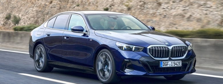 BMW i5 in blue driving on a country road