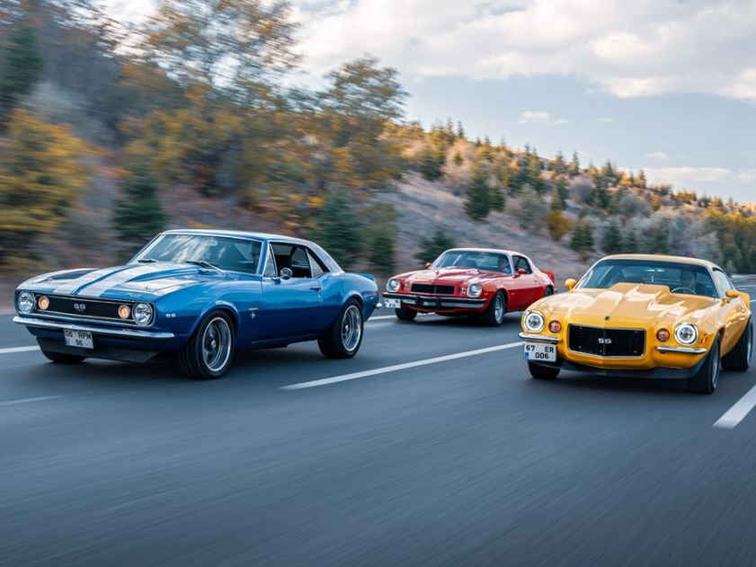 Old-school muscle cars driving on an open highway in Ankara, Türkiye, during fall.