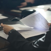 a woman sitting at a table reading a paper