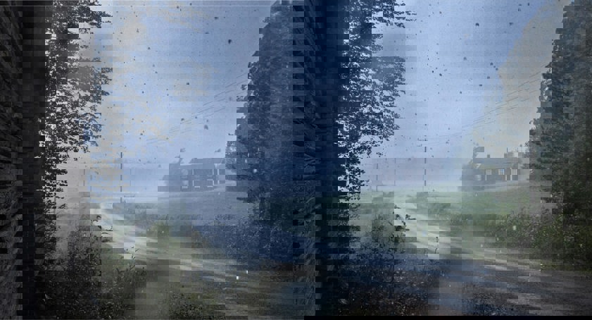 Rain storm with a house and road in the distance