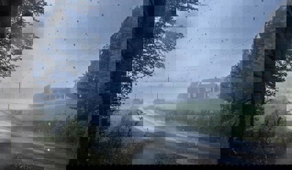Rain storm with a house and road in the distance