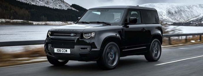 black land rover defender driving next to a lake