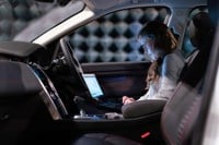 Woman using computer while sitting in driver seat of car