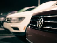 A row of luxury cars with a focus on the front grille, parked outdoors at night.