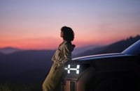 A woman sitting on the hood of a car