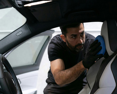 a man cleans seat inside car