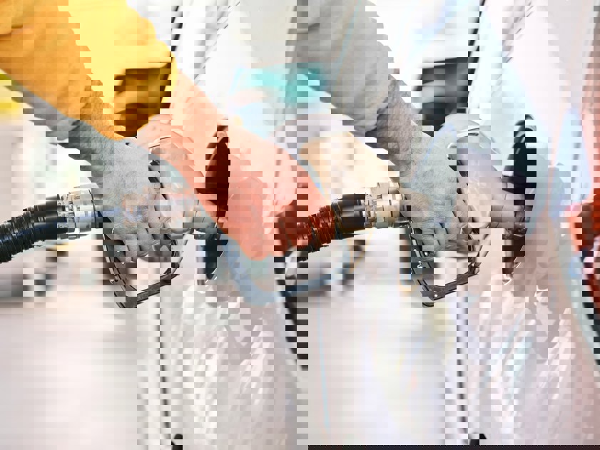 Closeup of man pumping gasoline fuel in car at gas station.