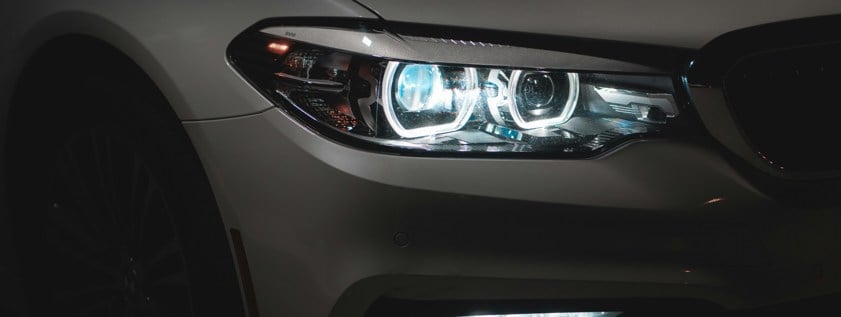 grey car with white and blue headlights