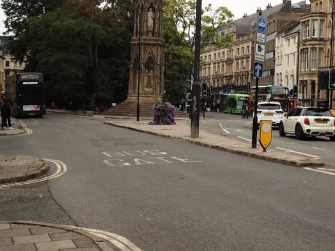 Street scene in Oxford featuring historic architecture and a central monument.