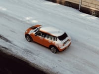 Aerial view of an orange car driving on a snowy street in Jönköping, Sweden.