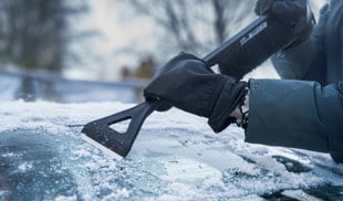 a person scraping ice from top of a car