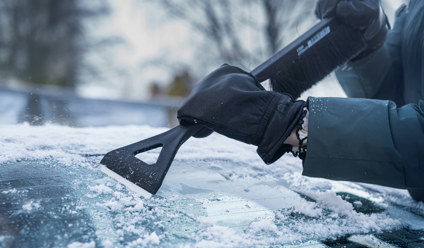 a person scraping ice from top of a car