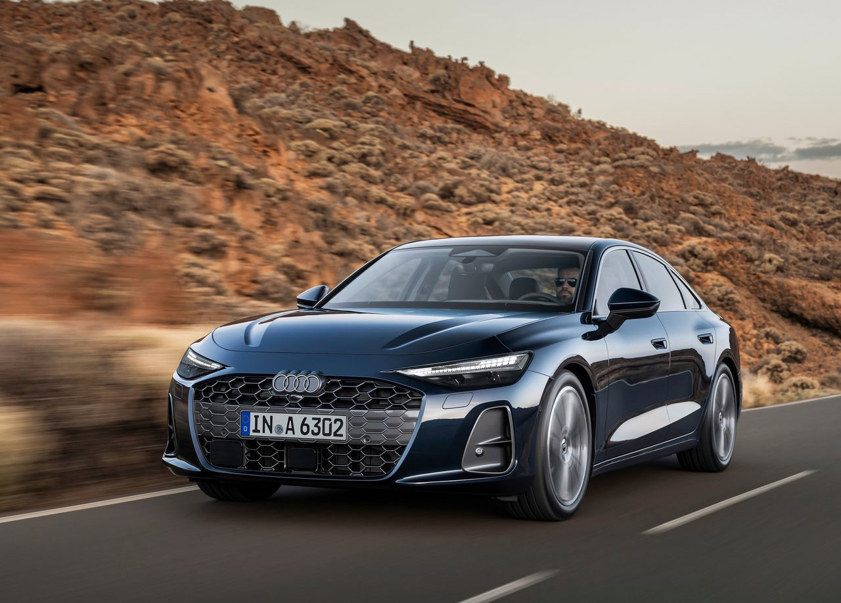 Audi A6 Saloon in navy driving on the road with rocky hills in the background