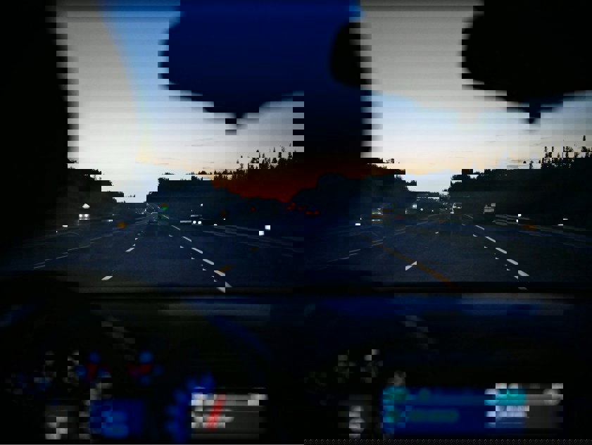 car dashboard with road in the background as the sun sets