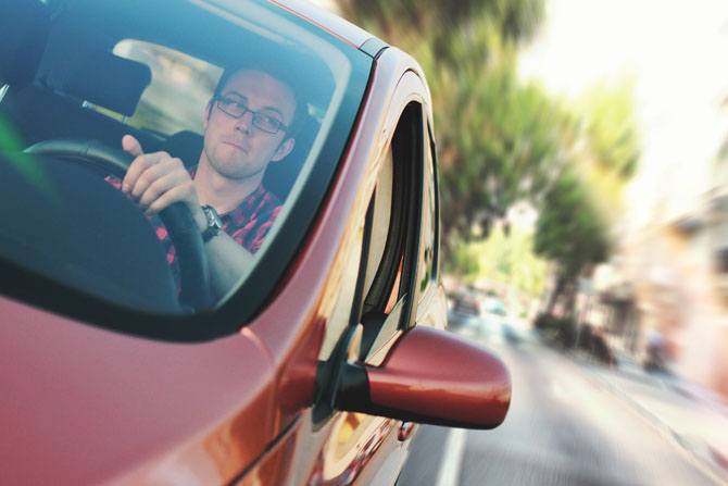 A close up of a young man driving a car.