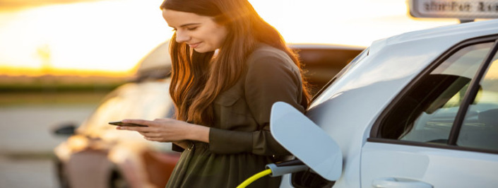 Women leaning on electric car charging