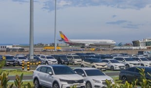 aeroplane taxiing on runway with cars in foreground