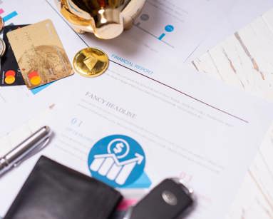 Close-up of financial documents, credit cards, coins, and a pen on a wooden desk.