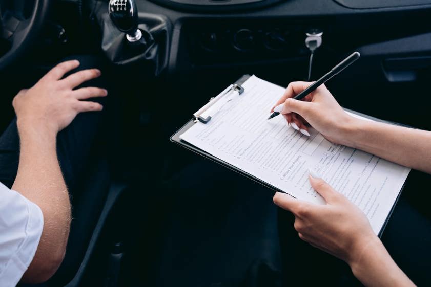 Person writing on a clipboard inside of a car