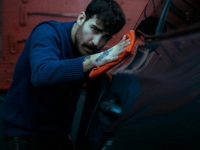 Man polishing a car in a garage