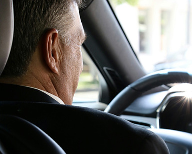 man in black suit driving car