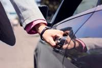 Person opening car door with hand on the door handle