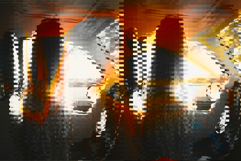woman driving car with sun coming through window