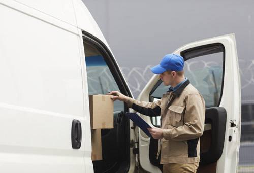 Courier checking the cardboard boxes in the van before shipping