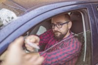 man in car handing over driving licence