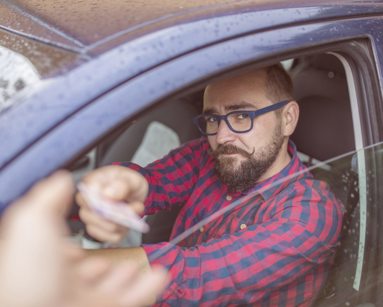 man in car handing over driving licence