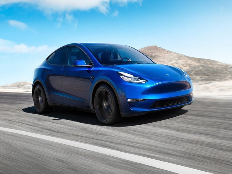blue tesla model y driving on the road