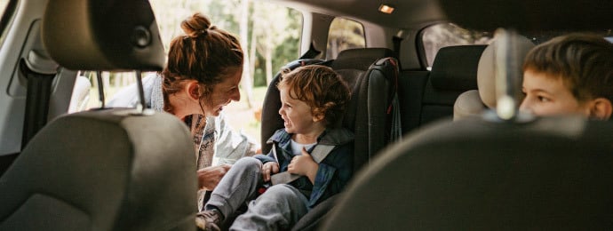 Mother happily checking on children in a car