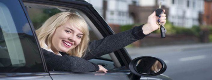 young woman holding car key with head out of window